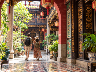Pareja de viajeros en un patio histórico de George Town, Penang
